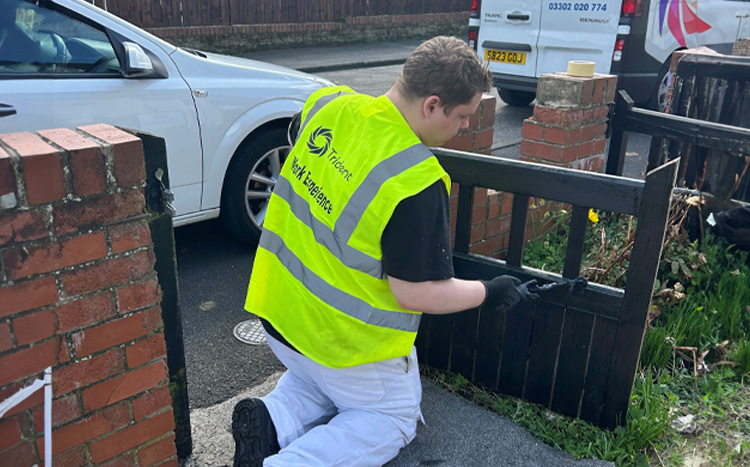 A member of the trident team painting a gate
